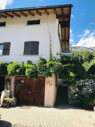 una casa blanca con una puerta y una valla en Chez Marilyne, en Savièse