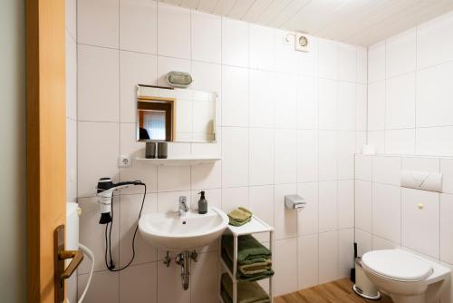 AssinghausenにあるFerienhaus Hedrichの白いバスルーム(洗面台、トイレ付)