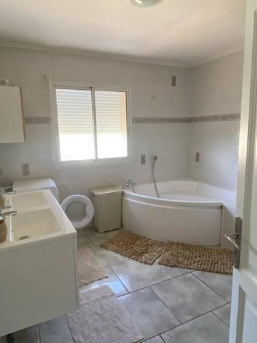 La salle de bains blanche est pourvue d'une baignoire et de toilettes. dans l'établissement Maison près des vignes, à Castelnau-de-Guers