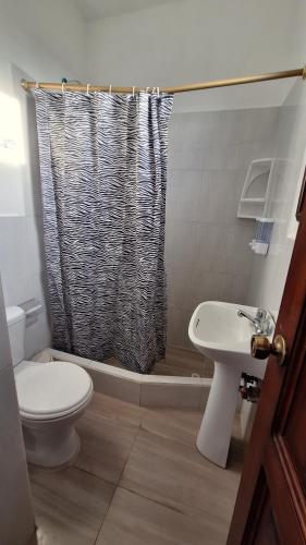 a bathroom with a toilet and a shower curtain at Galápagos Brunette Suites I in Puerto Ayora