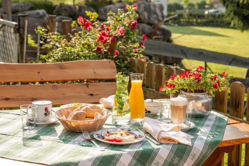 a picnic table with food and orange juice and flowers at Landhaus Aubauerngut in Radstadt