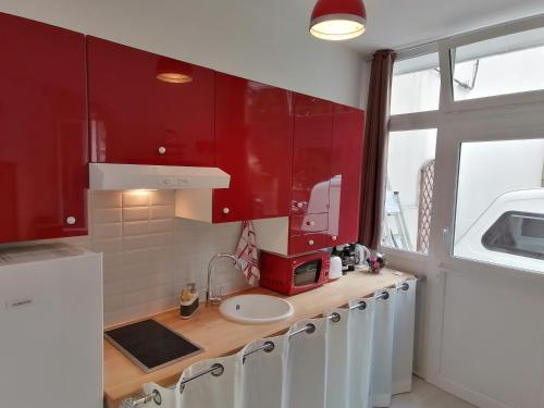 una cocina con armarios rojos y fregadero en Accessible Rouen, en Rouen