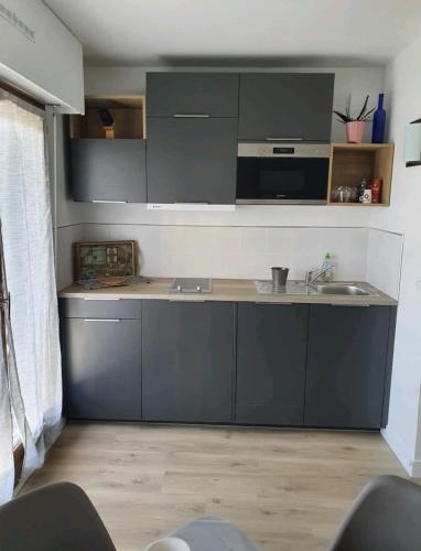 une cuisine avec des armoires grises et un évier dans l'établissement Super appartement en plein cœur de Deauville, à Deauville