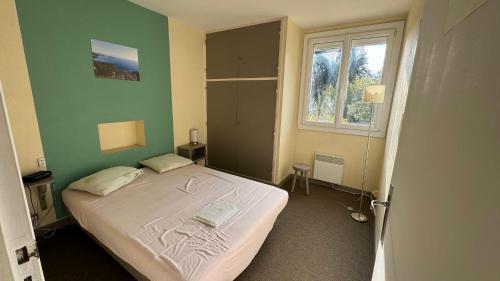 une chambre avec un lit dans une pièce verte dans l'établissement Appartement EST classé 3 étoiles au 1er étage d'une maison avec jardin dans un quartier calme, à Cavalaire-sur-Mer
