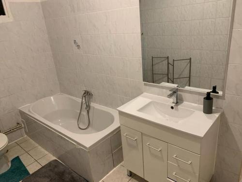 ein Badezimmer mit einer Badewanne, einem Waschbecken und einem Spiegel in der Unterkunft Sublime T4 à kourou avec piscine in Kourou