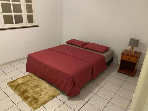 a bedroom with a bed with red sheets and a table at Sublime T4 à kourou avec piscine in Kourou