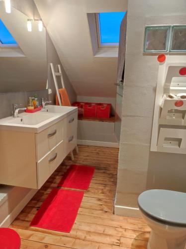 La salle de bains est pourvue d'un lavabo et d'un tapis rouge. dans l'établissement Chambres d'hôtes de charme sur LE MANS, au Mans