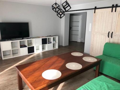 een woonkamer met een tafel en een groene bank bij Apartament Dominik in Głuszyca