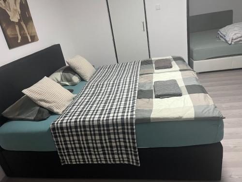 a bed with a checkered blanket and pillows on it at Apartmánek Patricie room with kitchenette suitable for 2 adults and 2 children in Mikulov