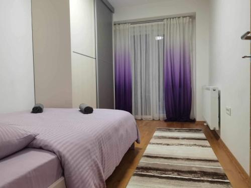 Schlafzimmer mit einem Bett und einem Fenster mit lila Vorhängen in der Unterkunft Fantasy - Strumica in Strumica