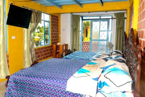 um quarto com duas camas e uma televisão na parede em Alex Country House em Chachagüí