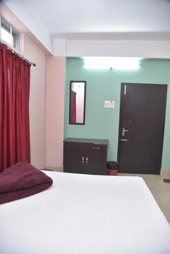 1 dormitorio con cama blanca y cortina roja en Bibhas Lodge & Restaurant en Guwahati