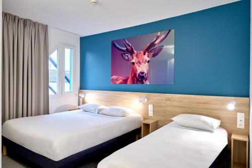 a hotel room with two beds with a deer on the wall at Kyriad Direct Nevers Nord - Varennes Vauzelles in Varennes Vauzelles
