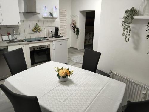 een witte tafel met een vaas met bloemen erop in een keuken bij Gemütliche Einliegerwohnung im Fachwerkhaus in Bröckel