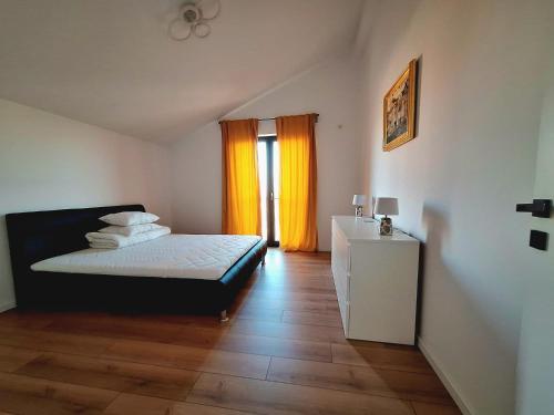 a bedroom with a bed and a window with orange curtains at Dalia One in Baloteşti