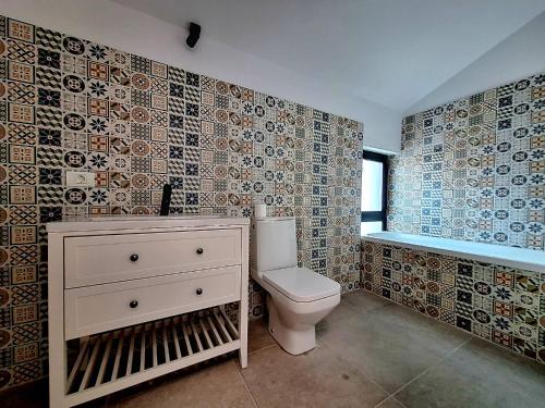 a bathroom with a toilet and tiles on the wall at Dalia One in Baloteşti