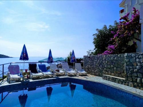 a swimming pool with lounge chairs and a stone wall at Villa Victoria in Utjeha