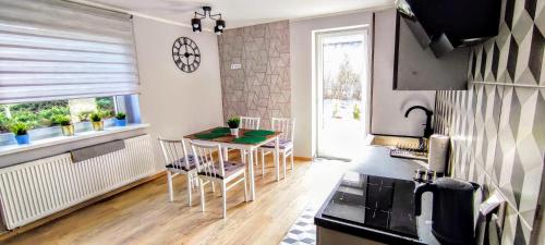 a kitchen with a table and chairs and a clock on the wall at Dom Przyjaźni in Kędzierzyn-Koźle