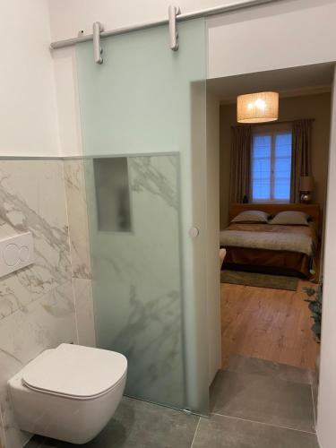 a bathroom with a toilet and a bedroom at Les Hortensias in Canly
