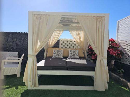 a bed with curtains and pillows on a balcony at Casa Villa Portuguesa (piscina climatizada) in Tahiche