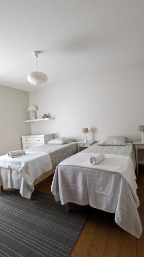 deux lits dans une chambre aux murs blancs et au parquet dans l'établissement Atelier Liberation, à Bourgoin-Jallieu