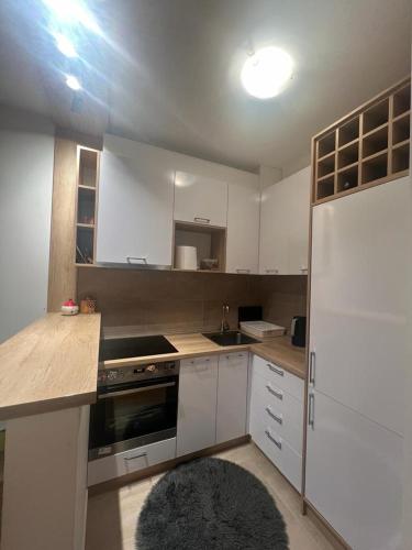 a kitchen with white cabinets and a white refrigerator at Jednosoban stan kod Aqua Parka in Ub