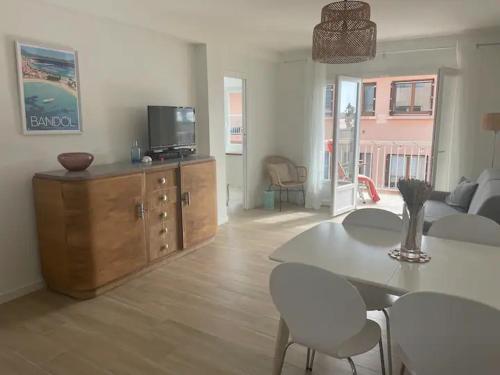 uma sala de estar com uma televisão e uma mesa e cadeiras em Très bel appartement vue mer em Six-Fours-les-Plages