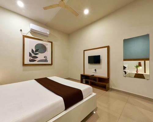 1 dormitorio con 1 cama y TV de pantalla plana en Serenity Resort Panhala, en Panhāla