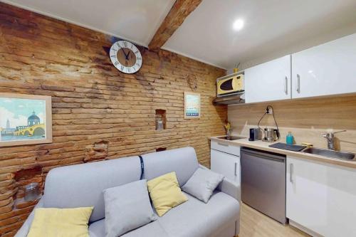 un salon avec un canapé et un mur de briques dans l'établissement Studio classé au cœur des Carmes, à Toulouse