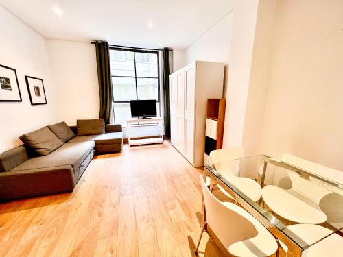 a living room with a couch and a television at Excellent Entire Apartment Between St Pauls Cathedral and Covent Garden in London