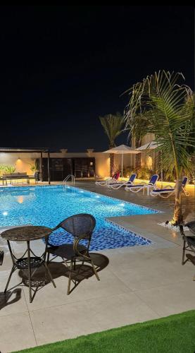 a swimming pool at night with chairs and a table at sea breeze RAK in Ras al Khaimah