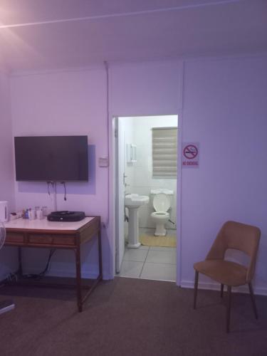 a purple room with a desk and a tv and a toilet at Achimer guesthouse in Kroonstad