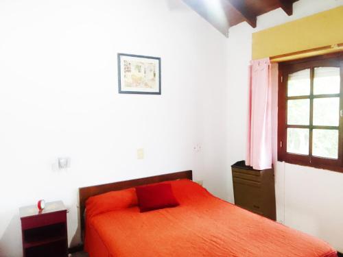 1 dormitorio con cama roja y ventana en Norte, 310 en Villa Gesell