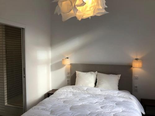 - une chambre avec un lit blanc et un lustre dans l'établissement 3 pièces Métro Marcel Sembat, à Boulogne-Billancourt