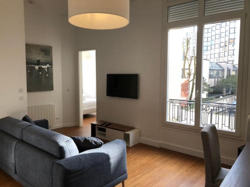 un salon avec un canapé et une télévision dans l'établissement 3 pièces Métro Marcel Sembat, à Boulogne-Billancourt