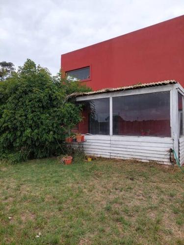 a red building with a window next to a yard at Casa a 500 metros del Mar in Quequén