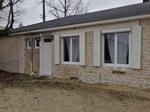 Una casa de ladrillo con dos ventanas y una puerta blanca en Au petit logement, en Soncourt-sur-Marne