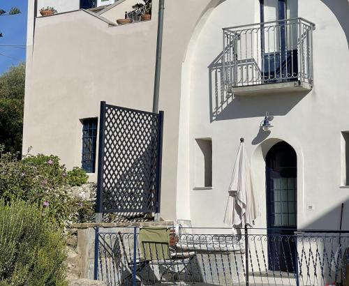 a white building with a balcony and an umbrella at Monolocale Sirena vista mare in San Marco di Castellabate