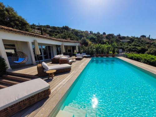 une piscine avec des chaises et une maison dans l'établissement Villa Les Agrumes vue panoramique sur mer, à La Croix-Valmer