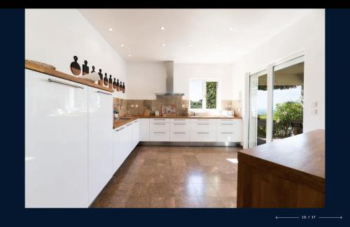 une cuisine avec des armoires blanches et un plancher en bois dans l'établissement Villa Les Agrumes vue panoramique sur mer, à La Croix-Valmer