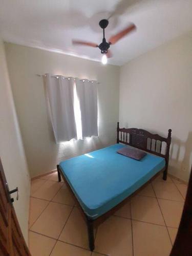 um quarto com uma cama azul e uma ventoinha de tecto em Excelente Localização em Jacaraípe em Serra