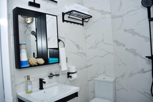 Zuri Luxe 2BR Beach apt.-Malindi في ماليندي: حمام أبيض مع حوض ومرآة