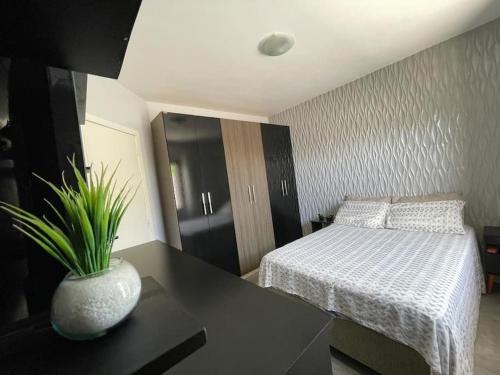 1 dormitorio con 1 cama y un jarrón sobre una mesa en Excelente localização a metros do mar e próximo a todos os recursos en Xangri-lá