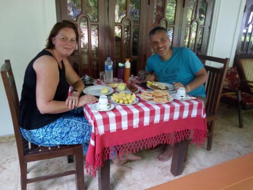 Ein Mann und eine Frau sitzen an einem Tisch mit Essen in der Unterkunft SMW Lodge Sigiriya in Sigiriya