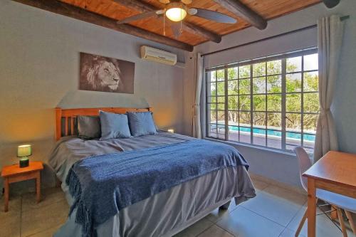 1 dormitorio con cama y ventana grande en Greater Kruger View - Luxury Bush Villa, en Marloth Park