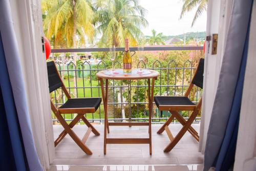 a table and two chairs on a balcony with a window at Czar's Oasis Apt B27 @ Ocho Rios in Ocho Rios
