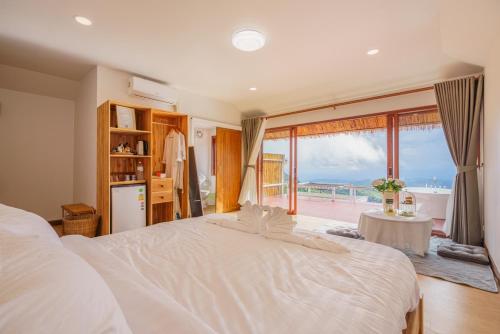 a bedroom with a large white bed with a view of the beach at Cozy Homey Doichang in Ban Muang Ngam