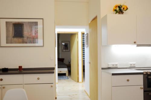 PAS 17 Apartment Berlin – cozy apartment في برلين: مطبخ مع دواليب بيضاء وممر مع غرفة نوم
