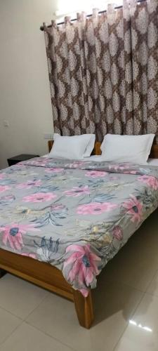 a bed with a floral comforter and a headboard at Service Apartment Near Rameshwaram Cafe Brookefield in Bangalore