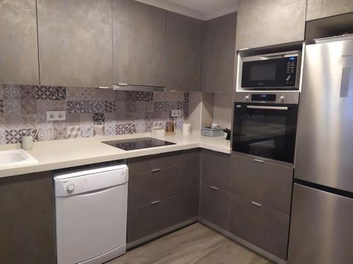 a kitchen with stainless steel appliances and a sink at Cozy duplex in old town Ondara in Ondara